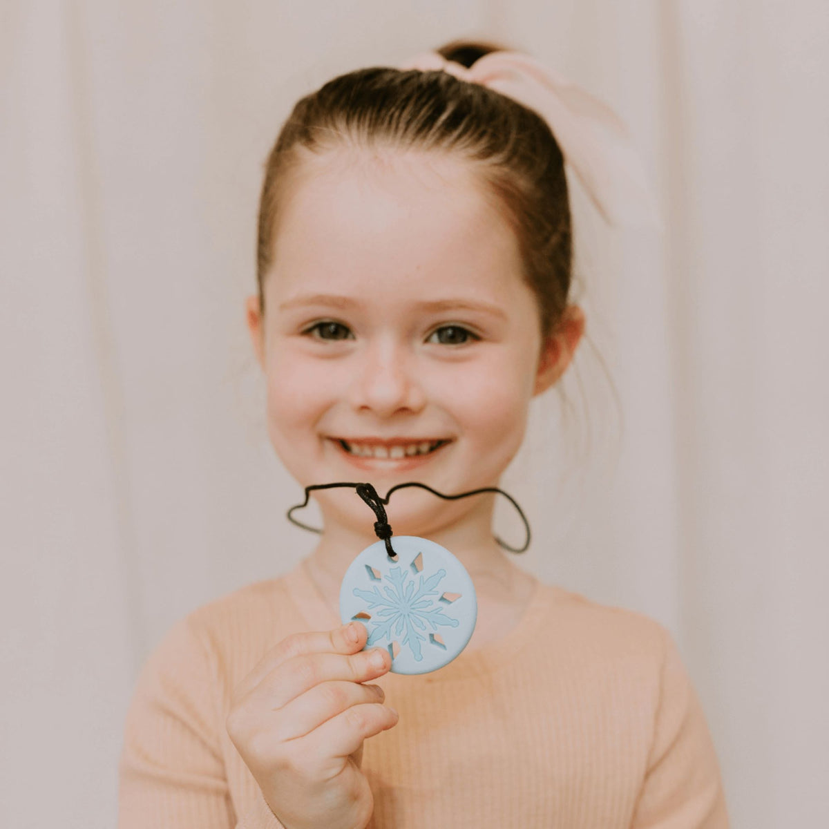 girl holding snowflake pendant daylight