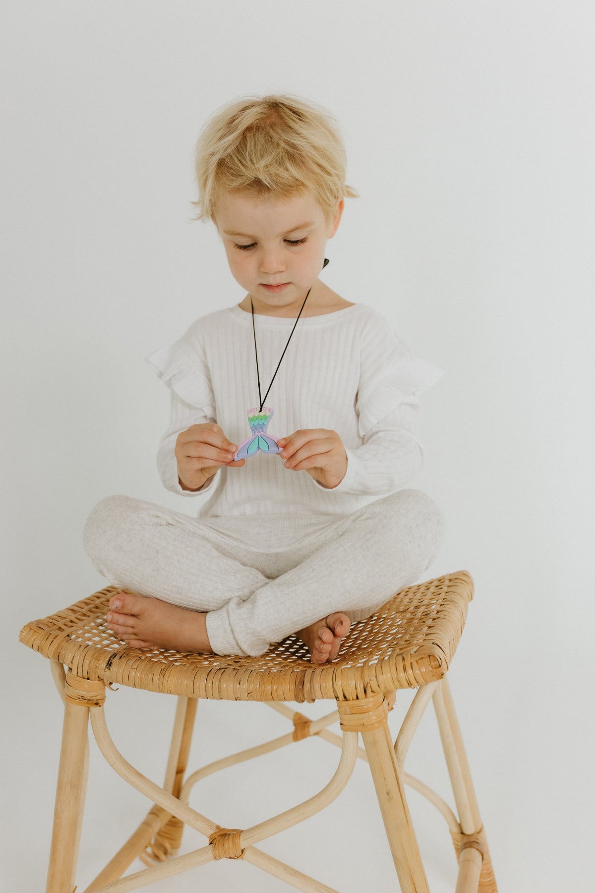 kid seating while holding her mermaid pendant