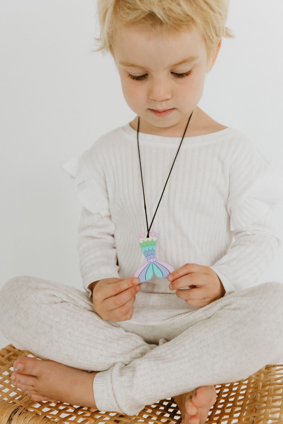 mermaid necklace being hold by a seating kid